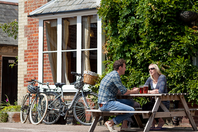 A couple enjoying a drink outside The Red Lion pub in Freshwater, Isle of Wight
