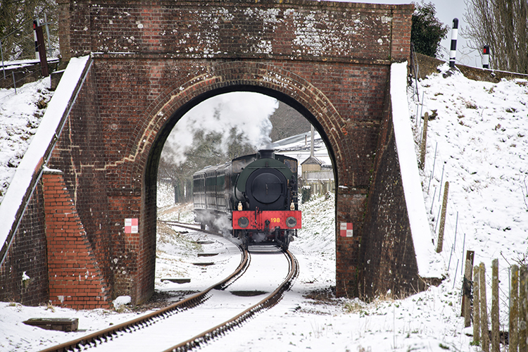 Steam train moving through the Isle of Wight countryside in winter