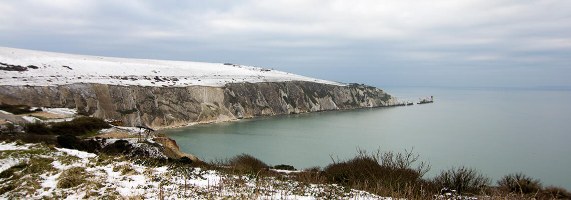 Snowy Isle of Wight coastline with The Needles under a winter sky